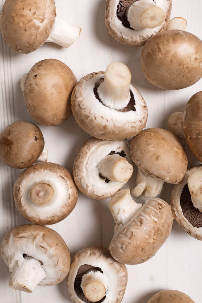 Fresh selection of chestnut mushrooms on a light wooden kitchen surface